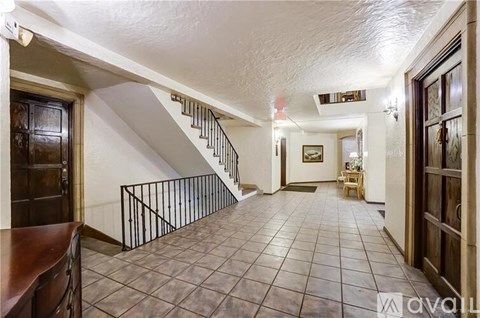 A hallway with a staircase and a door on the right.