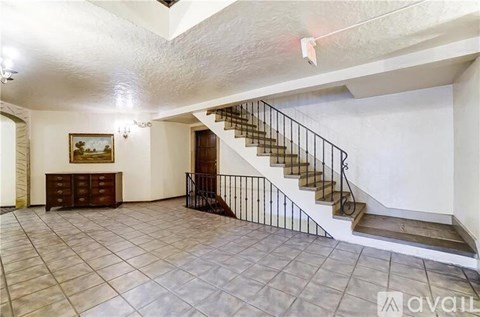 A spacious room with a staircase and a painting on the wall.