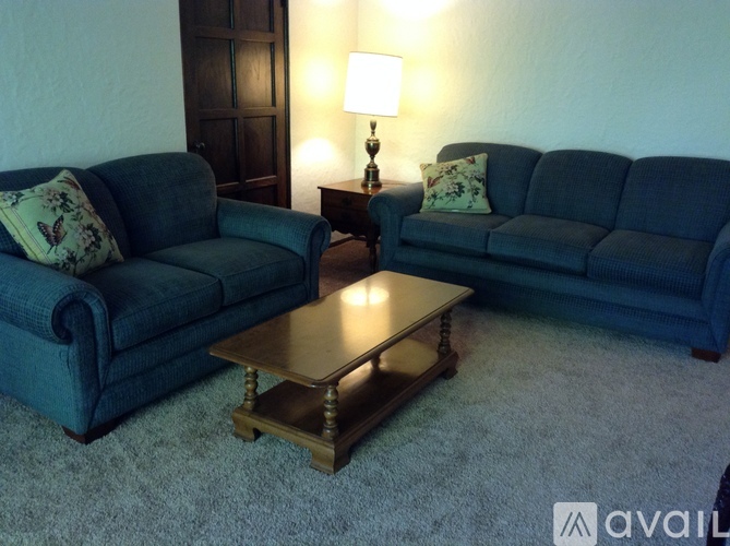 A living room with two blue couches and a wooden coffee table.