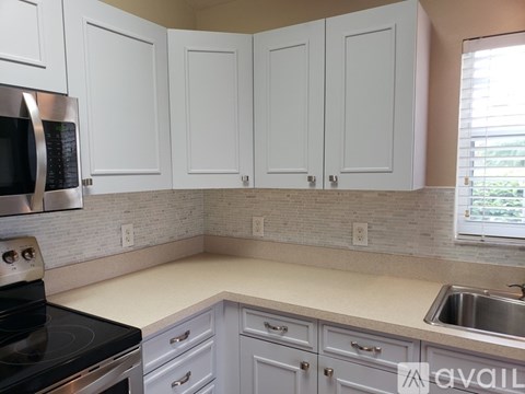 A kitchen with white cabinets and a black stove top.