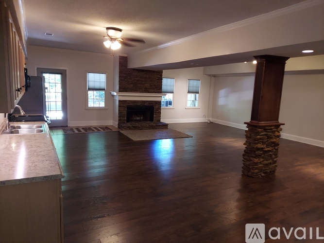 A spacious living room with a fireplace and a stone pillar.
