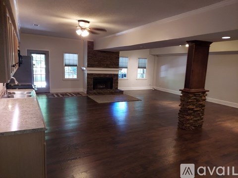 A spacious living room with a fireplace and a stone pillar.