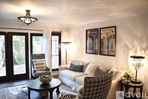 A living room with a white couch, a chair, a table, and pictures on the wall.