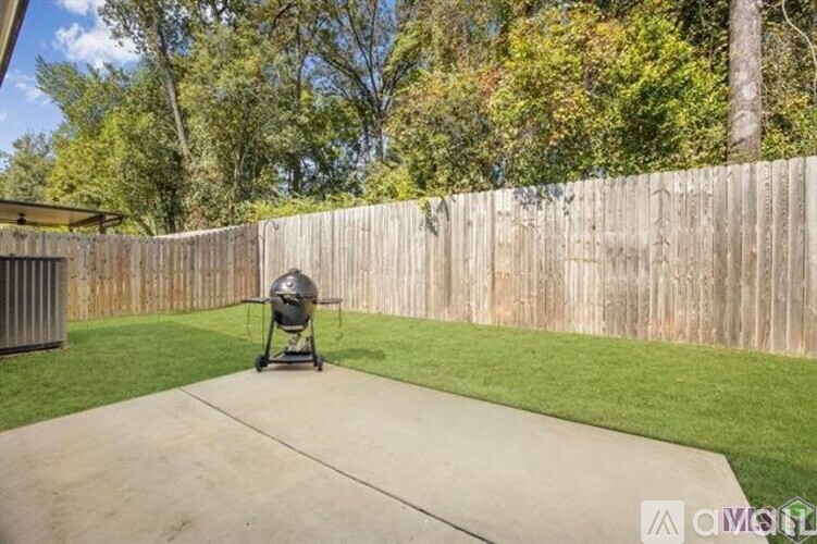 A backyard with a concrete walkway, a wooden fence, and a lawn chair.