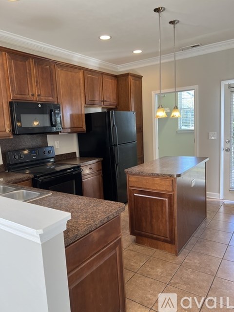 A kitchen with wooden cabinets and a black refrigerator.