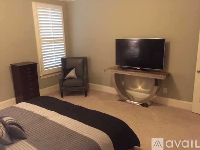 A bedroom with a bed, chair, and television.