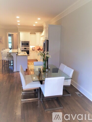 A modern dining room with a glass table and white chairs.