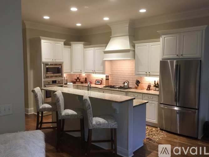 A kitchen with white cabinets and a marble countertop.