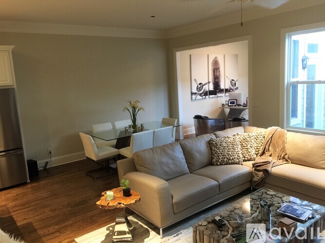 A living room with a grey couch and a painting on the wall.