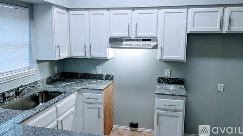 A kitchen with white cabinets and a granite countertop.