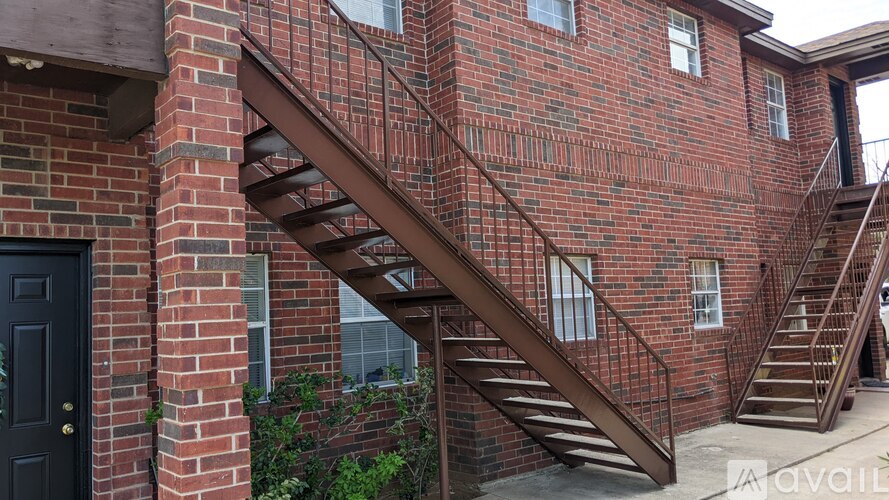 A brown wooden staircase leads up to a brick building.