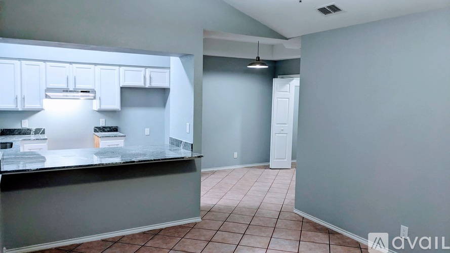A kitchen with white cabinets and a black countertop is available for rent.