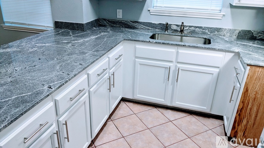A kitchen with white cabinets and a marble countertop.