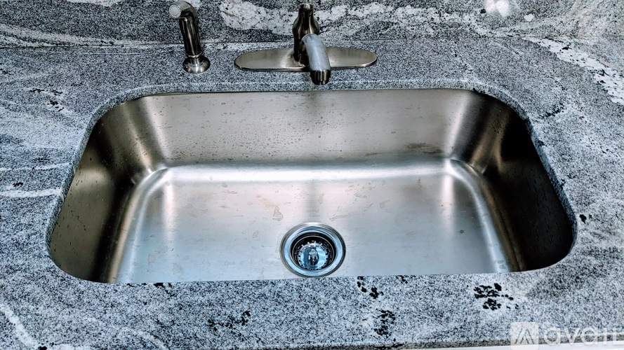 A stainless steel kitchen sink with a drain in the middle.