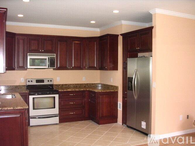 A kitchen with brown cabinets and a stainless steel refrigerator.