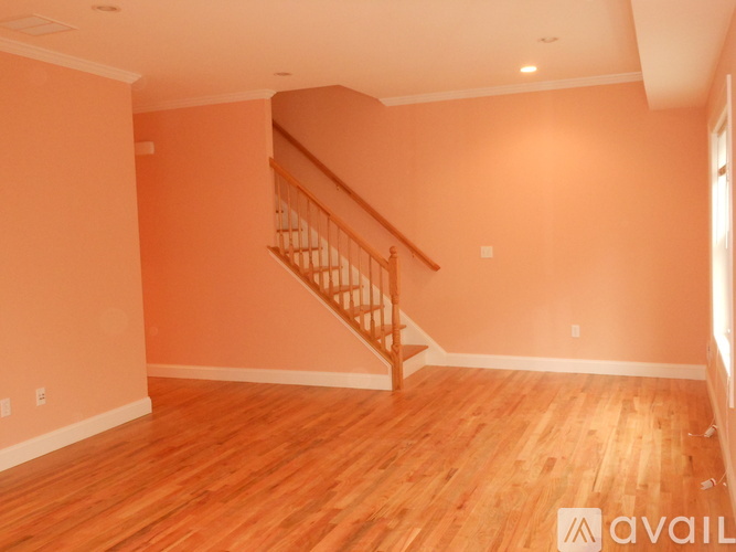 A room with a wooden staircase and hardwood floors.
