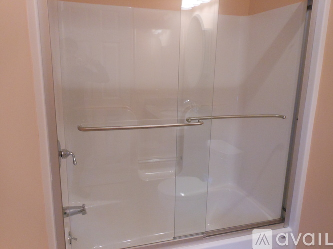 A glass shower door with a silver handle is installed in a bathroom.