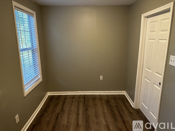 A room with a white door and a window with blinds.