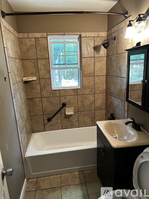 A bathroom with a tub, sink, and window.