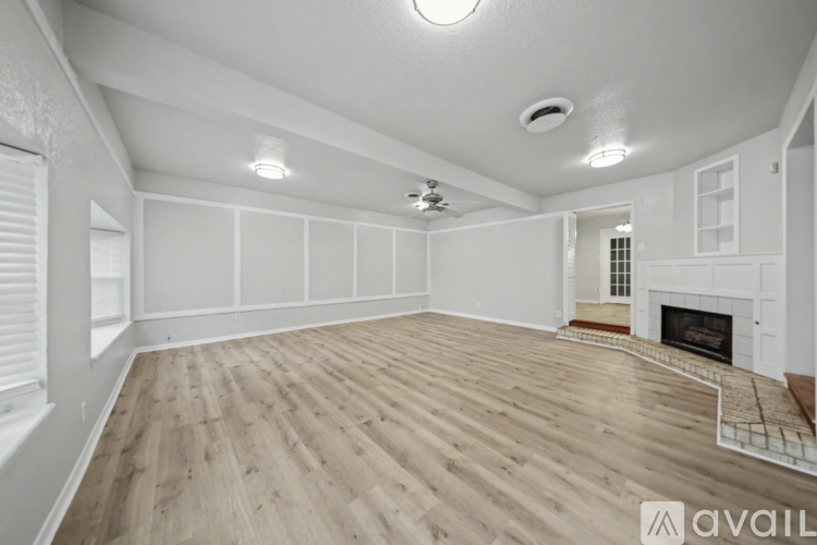 A spacious room with wooden flooring and a fireplace.