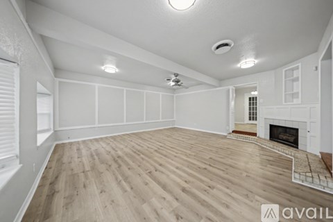 A spacious room with wooden flooring and a fireplace.