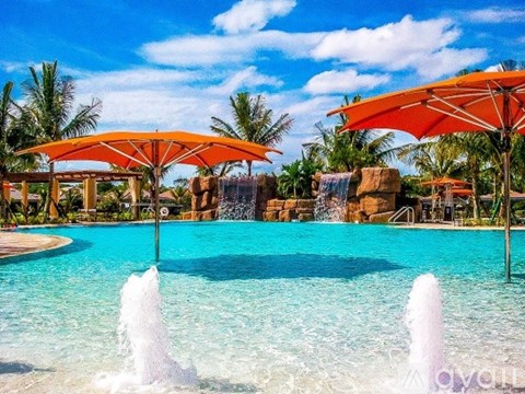 A pool with a waterfall and two umbrellas.