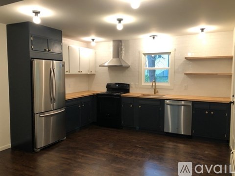 A kitchen with black cabinets and a stainless steel refrigerator.