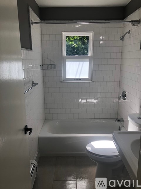 A bathroom with a toilet, tub, and window.