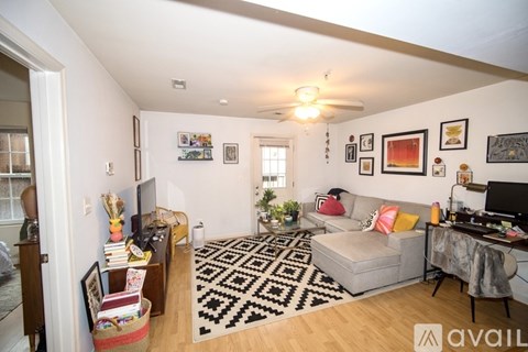 A living room with a couch, a rug, and a ceiling fan.