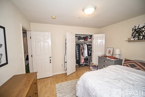 A bedroom with a bed, dresser, and closet.