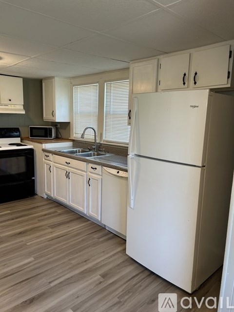 A kitchen with a white fridge, cabinets and microwave.