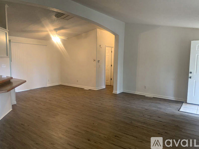A room with wooden flooring and white walls, with a door on the right side.