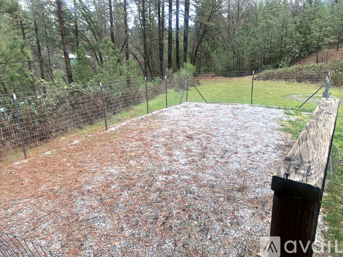 A backyard with a fence and a dirt area.