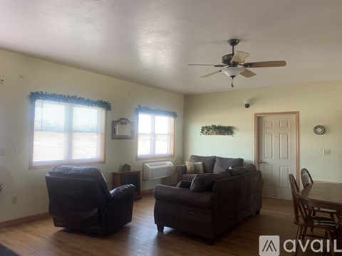 A living room with a brown couch, a chair, and a ceiling fan.