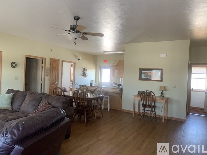 A living room with a brown couch and a dining table with chairs.