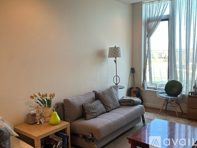A living room with a grey couch, a coffee table, and a guitar.
