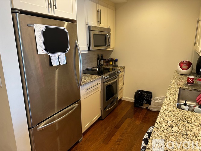 A kitchen with a stainless steel refrigerator and a granite countertop.