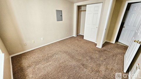 A carpeted room with a door and a window.