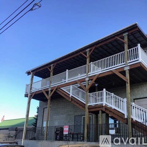 A wooden balcony with white railings is attached to a building.