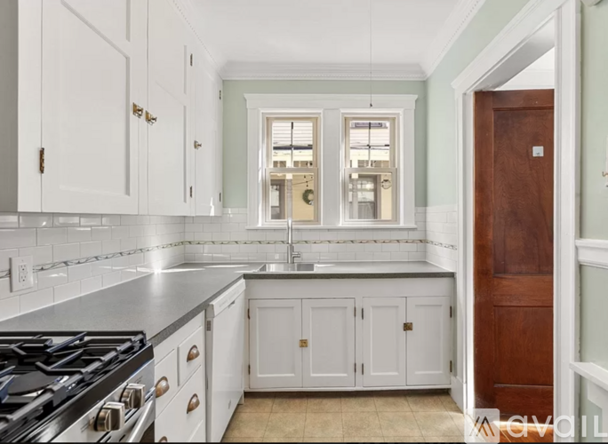 A kitchen with white cabinets and a black stove top oven.
