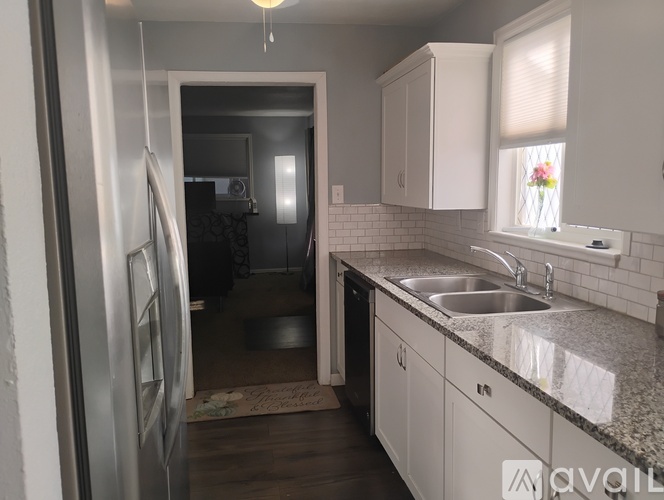 A kitchen with a sink, refrigerator, and cabinets.