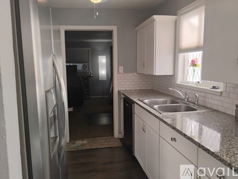 A kitchen with a sink, refrigerator, and cabinets.
