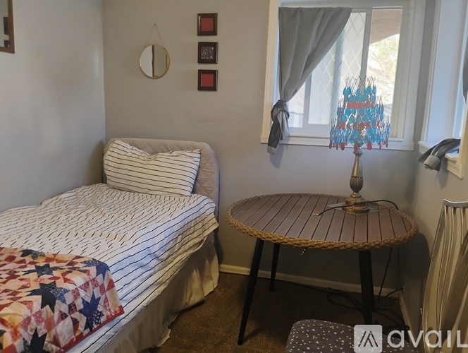 A bedroom with a bed, a round table, and a window with curtains.