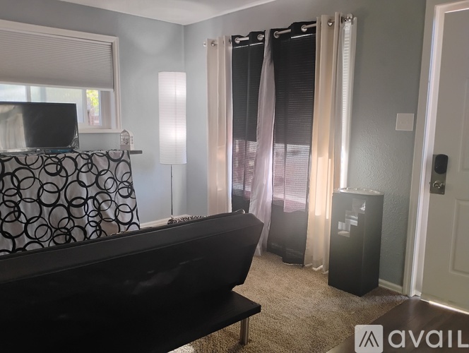 A living room with a black couch and a television on a black stand.