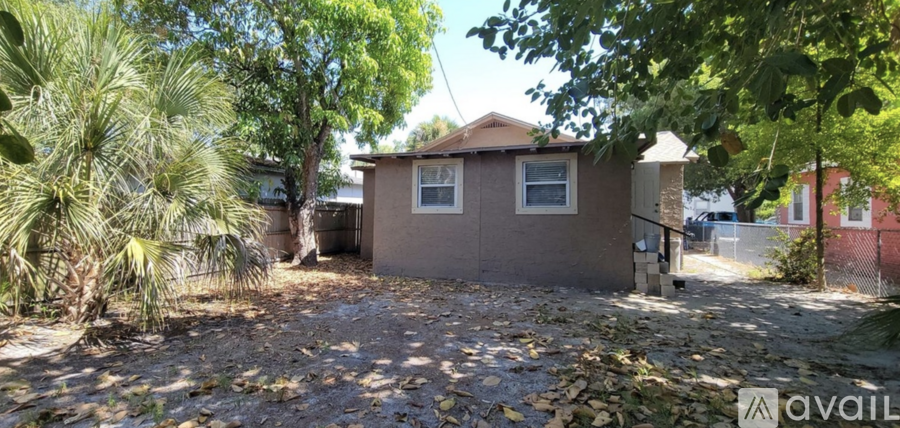 A house with a brown roof and a brown fence is surrounded by trees.