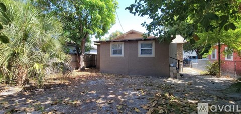 A house with a brown roof and a brown fence is surrounded by trees.