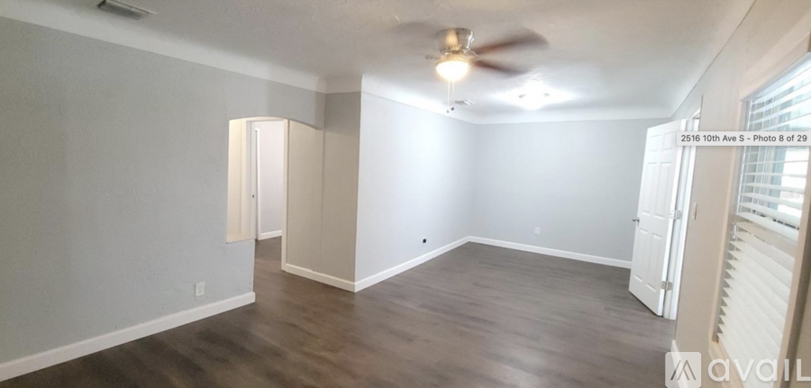 A spacious room with a ceiling fan and light fixture, and a window with blinds.