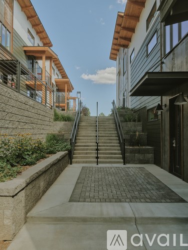 A set of stairs leads up to a building with a stone wall on one side and a metal railing on the other.