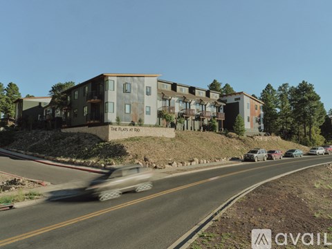 A car is driving on a road in front of a building called "The Flats at Rio".