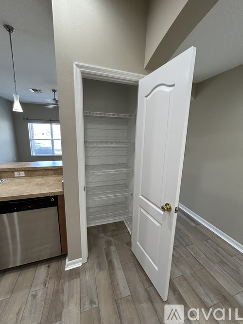 A white door is open to a room with a wooden floor.